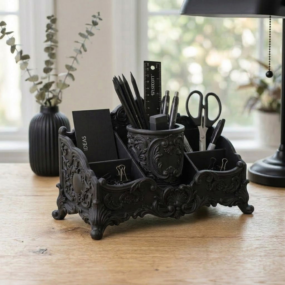 Black baroque desk organizer with pens, scissors, notebook, and stationery