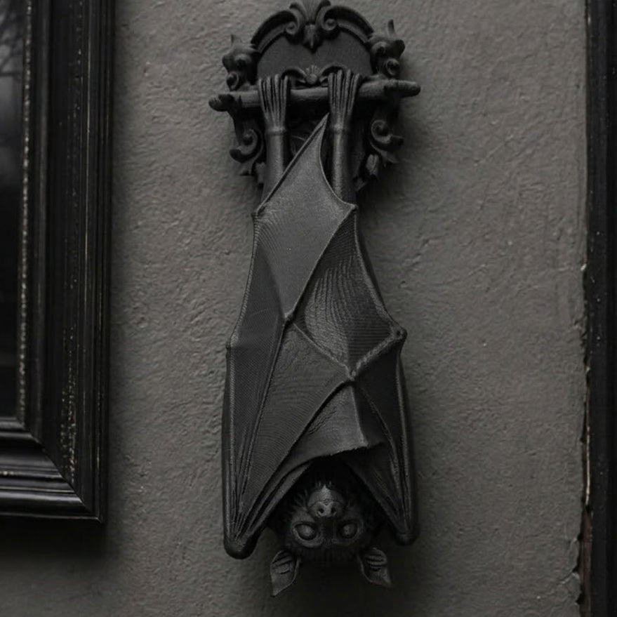 A matte black gothic bat wall decor sculpture hanging in a slightly closer view